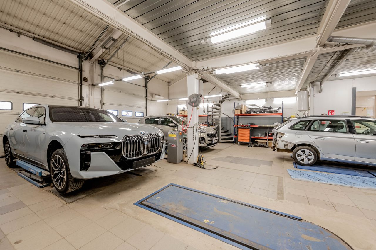 Spacious indoor car garage featuring luxury vehicles under maintenance, showcasing an organized and professional workspace.