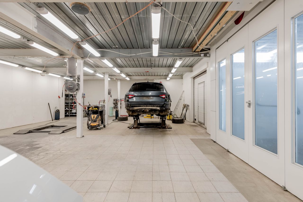 Well-lit garage with a car on a hydraulic lift ready for repair.