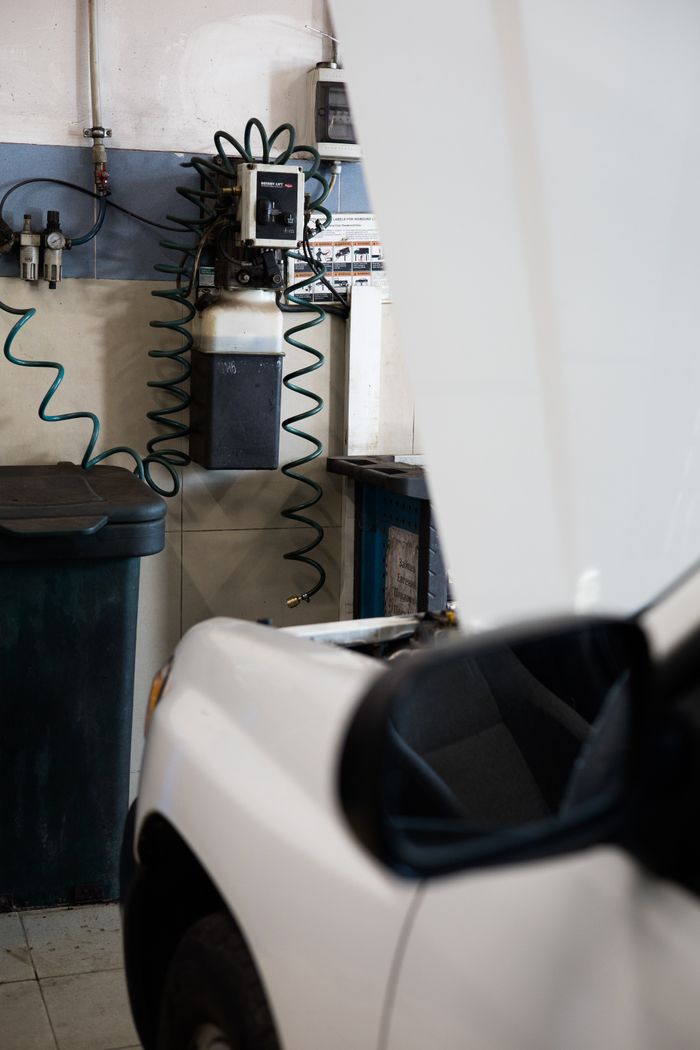 White car under maintenance in a well-equipped garage with tools and machines.